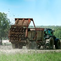 tracteur agricole avec remorque épandage de fumier en action sur le champ